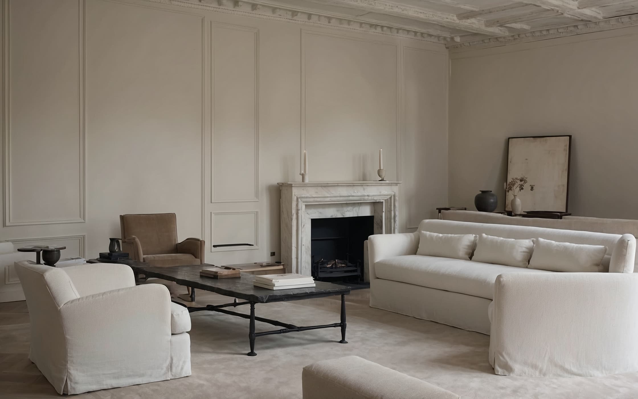 High-ceilinged Parisian salon with limestone fireplace, boiserie walls, linen sofa, overcast light